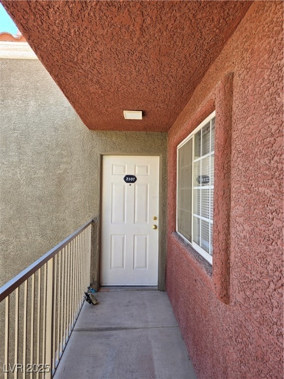 Property entrance with stucco siding and a balcony