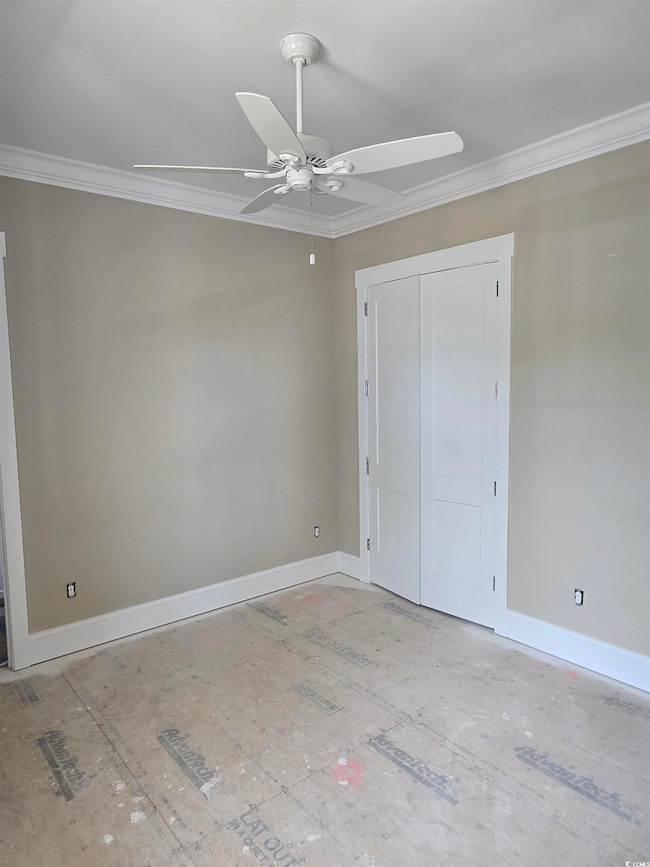 Unfurnished bedroom featuring crown molding, baseboards, ceiling fan, and a closet