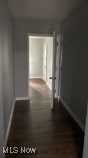 Corridor featuring baseboards and dark wood-type flooring