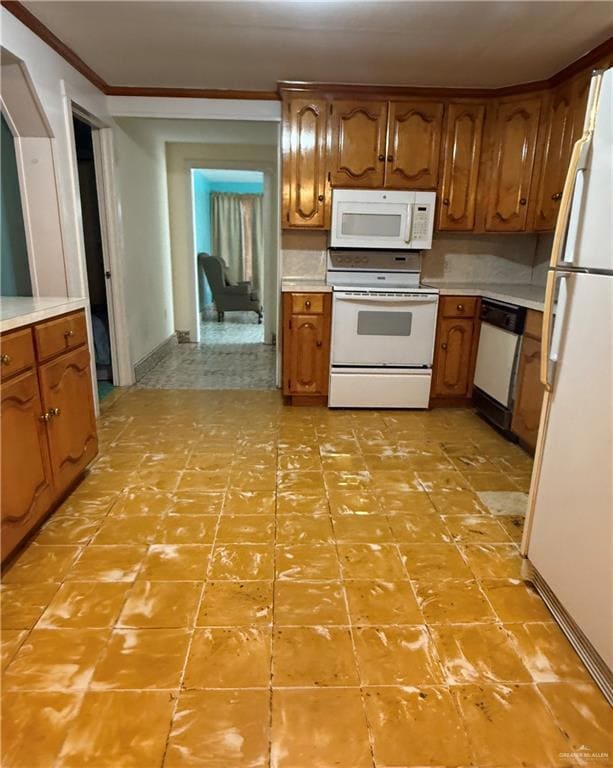 Kitchen with white appliances, brown cabinets, light countertops, and crown molding.