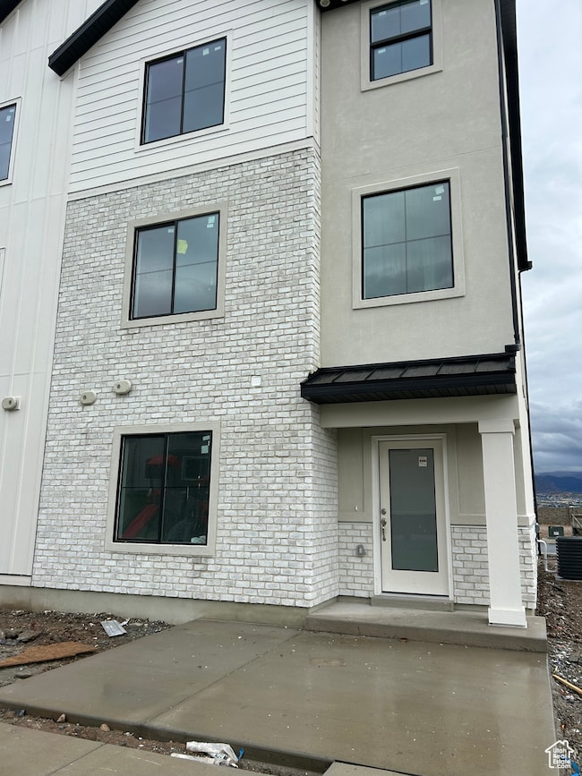 View of front facade featuring brick siding, board and batten siding, and stucco siding