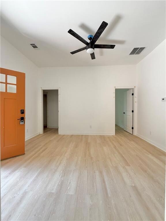 Living room featuring light wood-style floors, baseboards, a ceiling fan, and visible vents