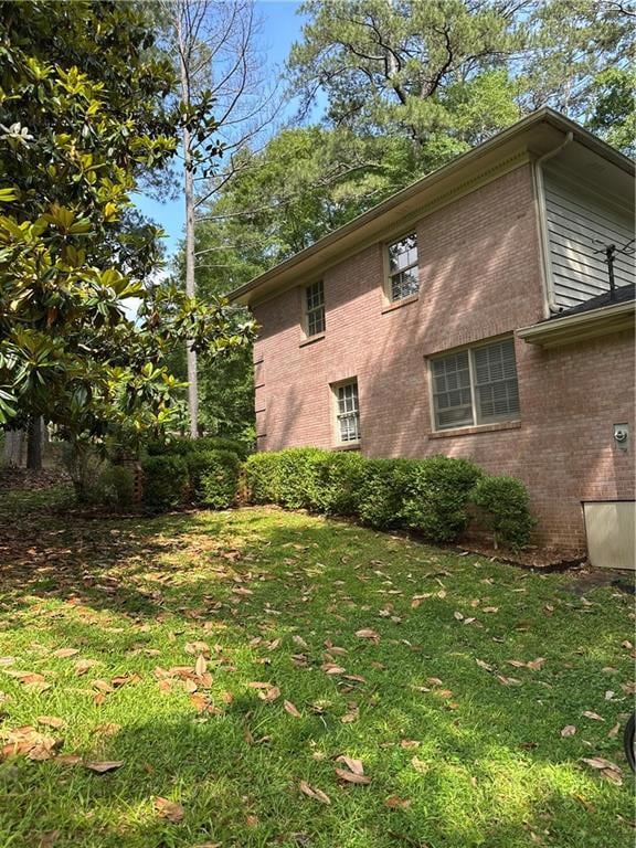 View of property exterior featuring brick siding and a yard