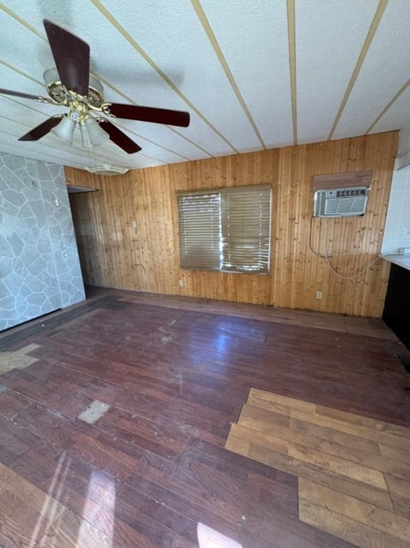 Spare room with wood walls, dark wood finished floors, and a ceiling fan