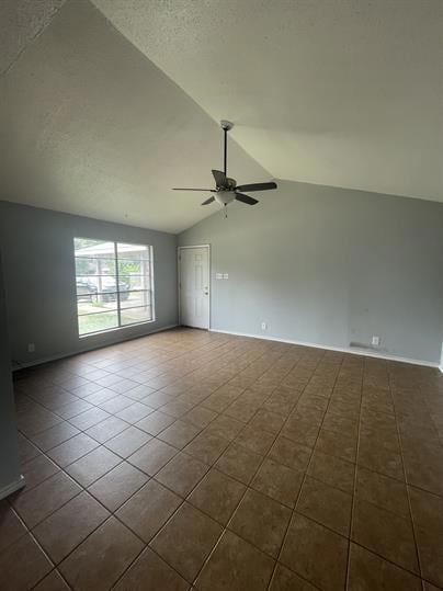 Empty room featuring a ceiling fan, vaulted ceili