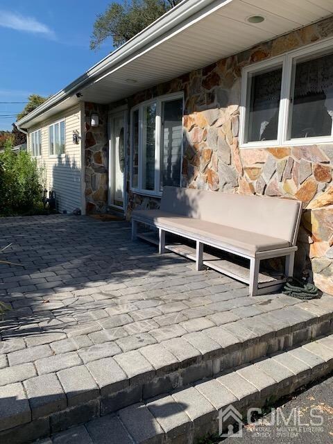 Front view of home features raised paver porch. Shows kitchen window and bay window in entry.