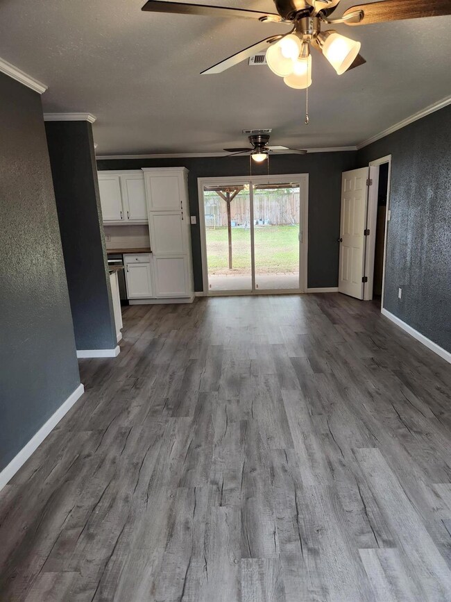 Unfurnished living room with crown molding, wood-t