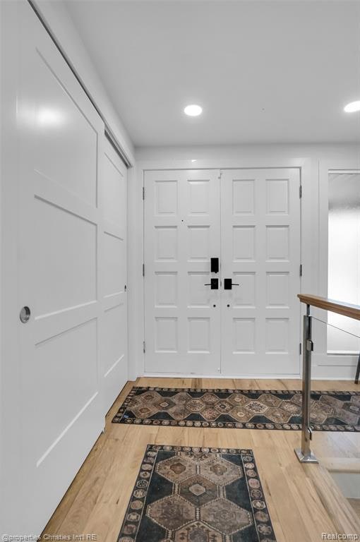 Foyer entrance with light wood finished floors and recessed lighting