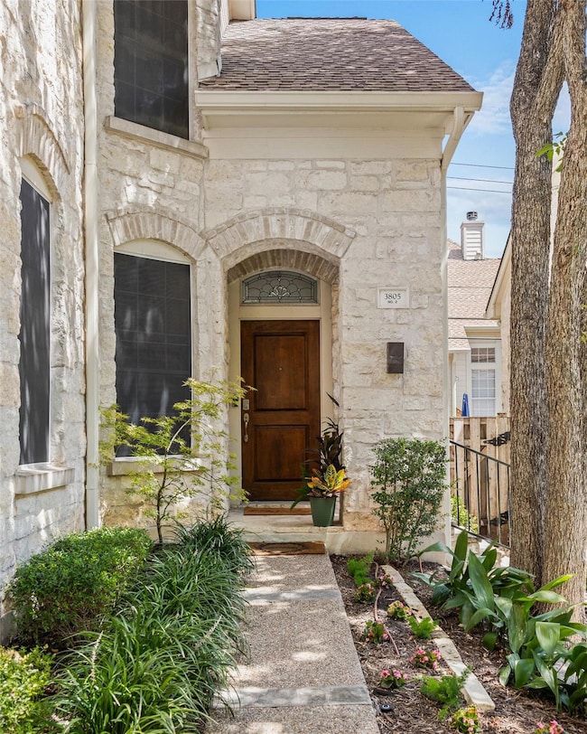 Entrance to property with stone siding and roof with shingles