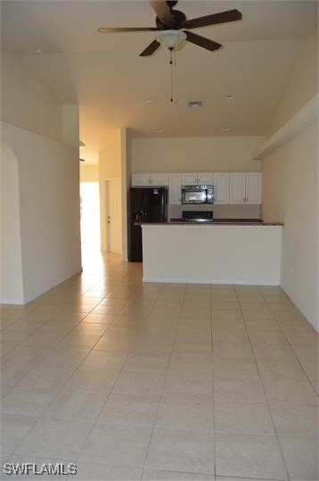 Kitchen with black fridge, light tile patterned fl