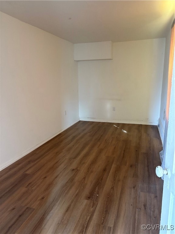 Spare room featuring dark wood-type flooring and b