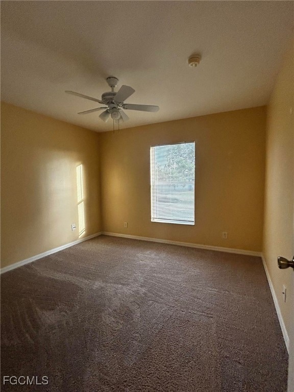 Spare room with dark colored carpet and baseboards