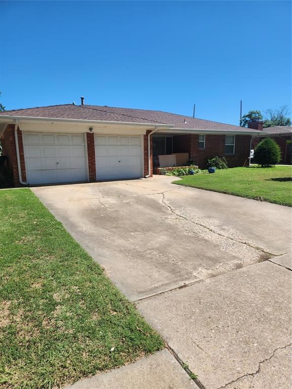 Single story home featuring a garage and a front y