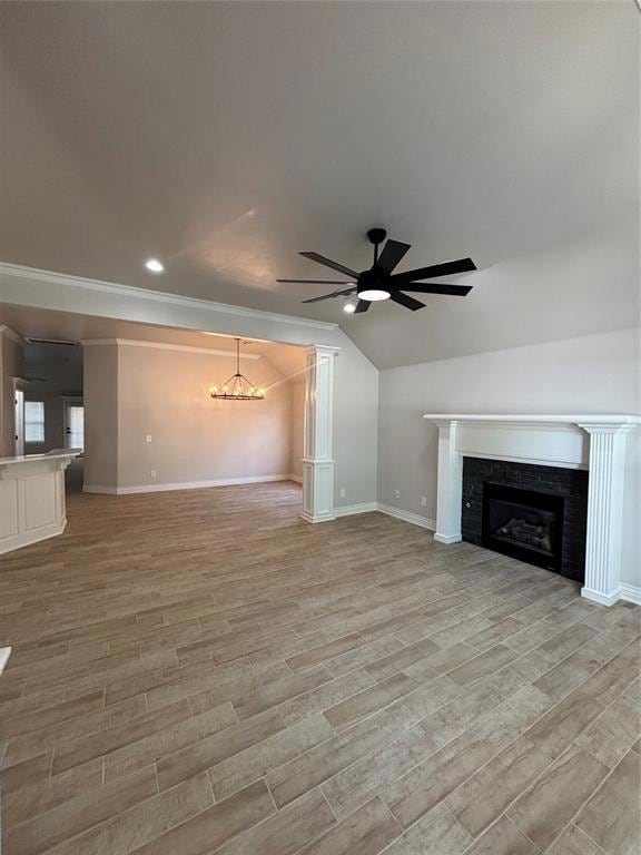 Unfurnished living room featuring a chandelier, a fireplace, ceiling fan, light wood finished floors, and baseboards