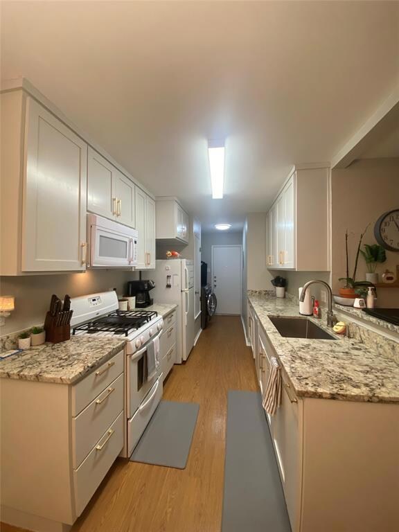 Kitchen featuring white appliances, a sink, light