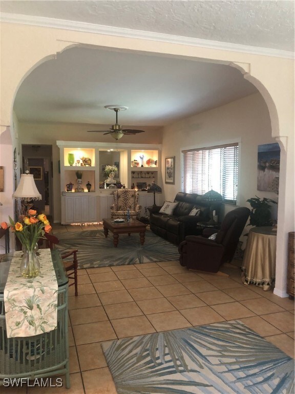 Living area featuring a ceiling fan, light tile pa