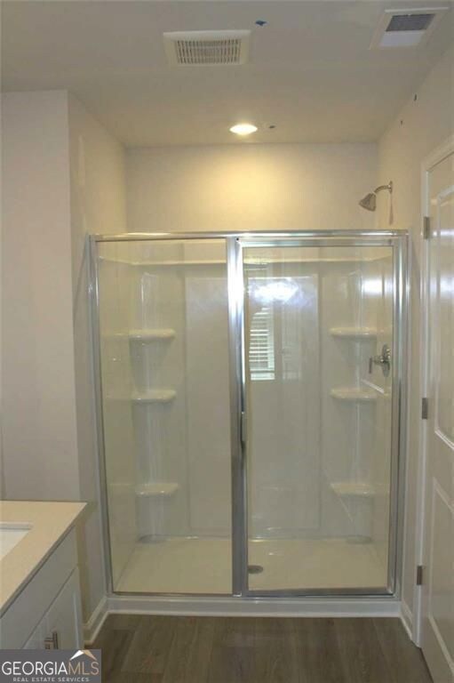 Full bath with a stall shower, vanity, wood finished floors, and recessed lighting