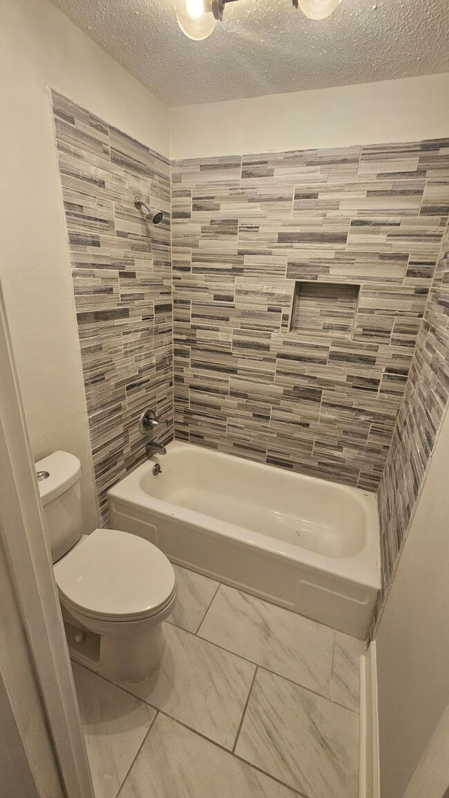 Bathroom featuring tiled shower / bath combo, toil
