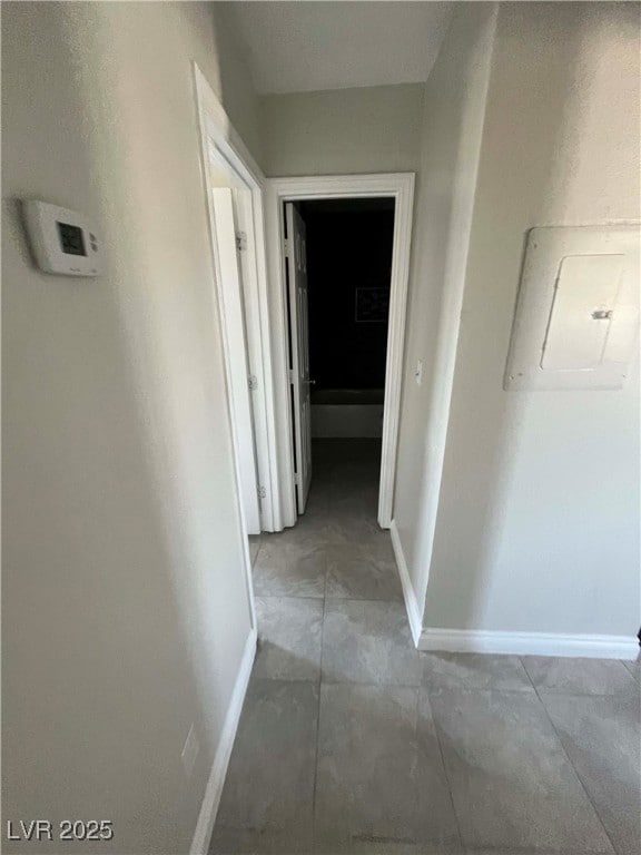 Corridor featuring baseboards, electric panel, and