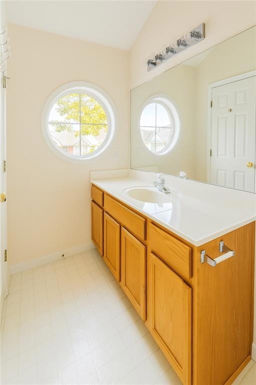 Bathroom featuring vanity, light floors, and lofted ceiling