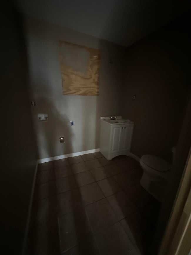 Clothes washing area featuring tile patterned floors and baseboards