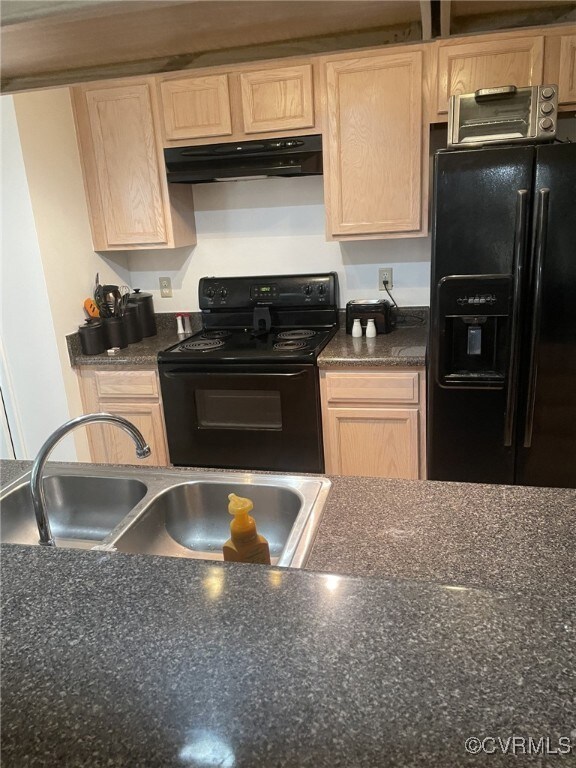 Kitchen with light brown cabinetry, black appliances, extractor fan, and sink