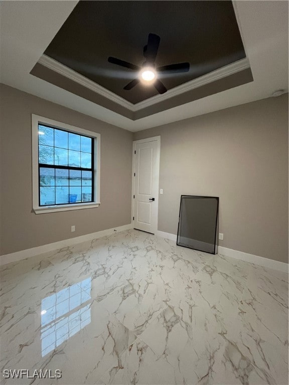 Empty room with ceiling fan, a raised ceiling, and