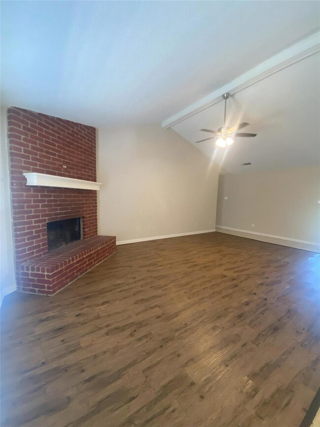 Unfurnished living room with lofted ceiling with beams, ceiling fan, dark hardwood / wood-style flooring, and a fireplace