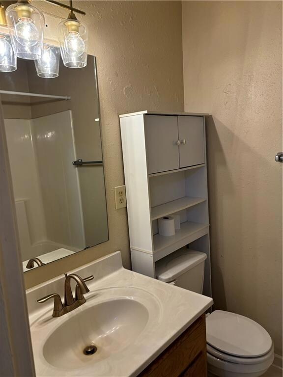 Bathroom featuring walk in shower, toilet, and vanity