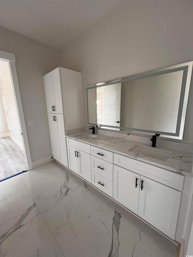 Full bathroom with double vanity, baseboards, marb