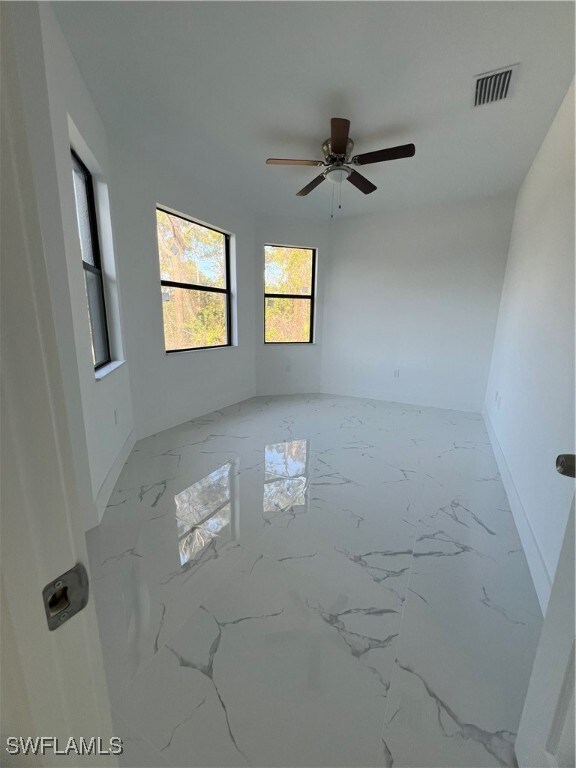 Spare room featuring a ceiling fan, marble finish