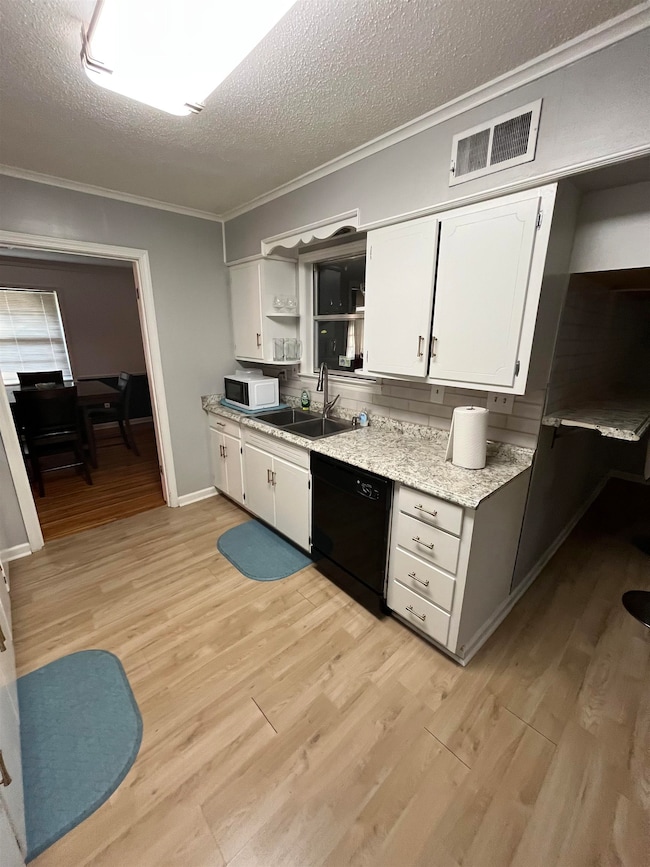 Kitchen featuring white cabinetry, a textured ceiling, ornamental molding, open shelves, and light wood-style floors