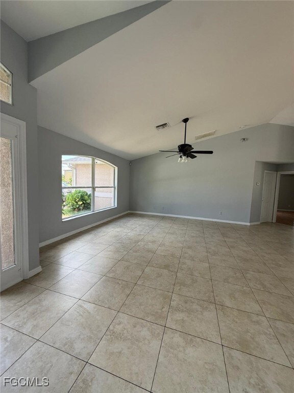 Empty room with lofted ceiling, ceiling fan, and l
