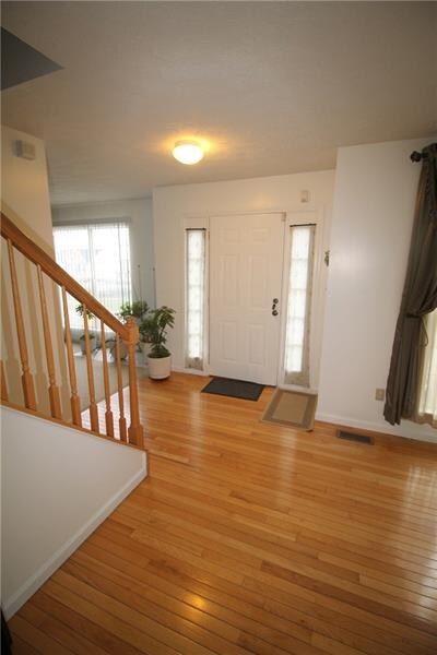 The entry features a hardwood floor an has a guest