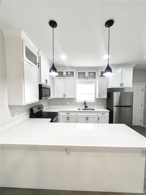 Kitchen with glass insert cabinets, white cabinetry, appliances with stainless steel finishes, hanging light fixtures, and a peninsula