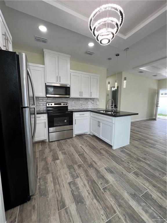 Kitchen featuring dark hardwood / wood-style floors, tasteful backsplash, fridge, range, and hanging light fixtures