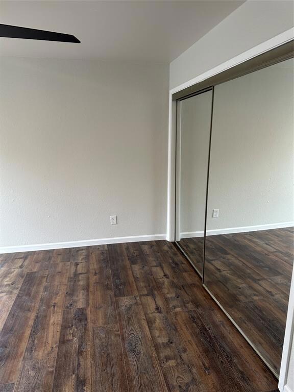 Unfurnished bedroom with dark wood-style flooring, a closet, and ceiling fan