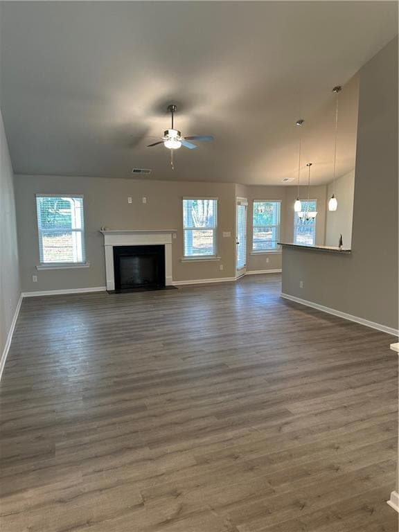 Unfurnished living room featuring a fireplace, dark wood finished floors, and ceiling fan