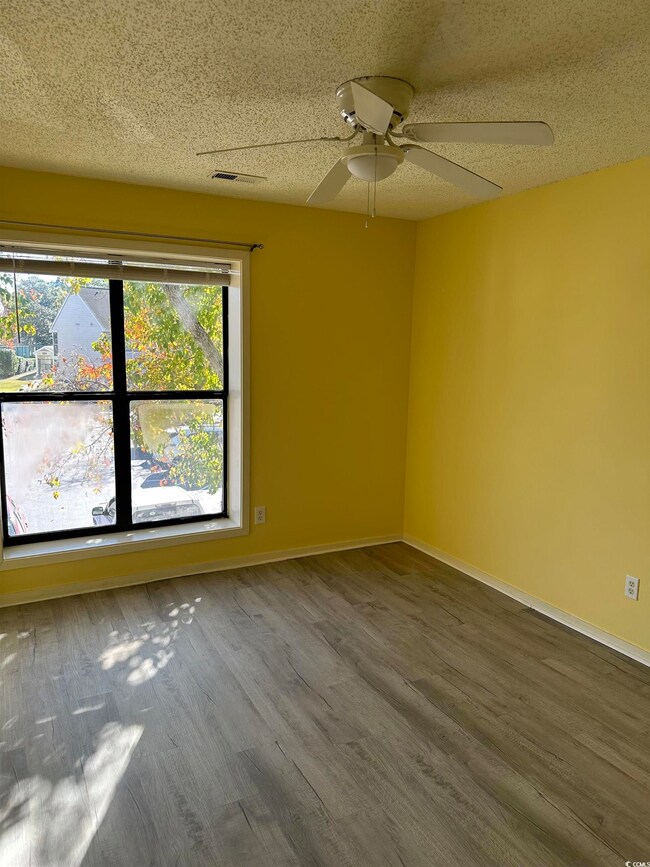 Spare room with a textured ceiling, wood finished floors, and ceiling fan