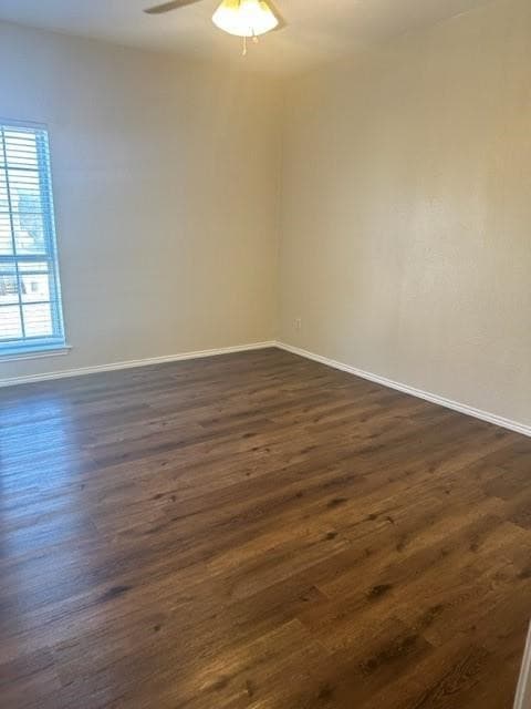 Empty room with dark wood-style flooring and ceiling fan