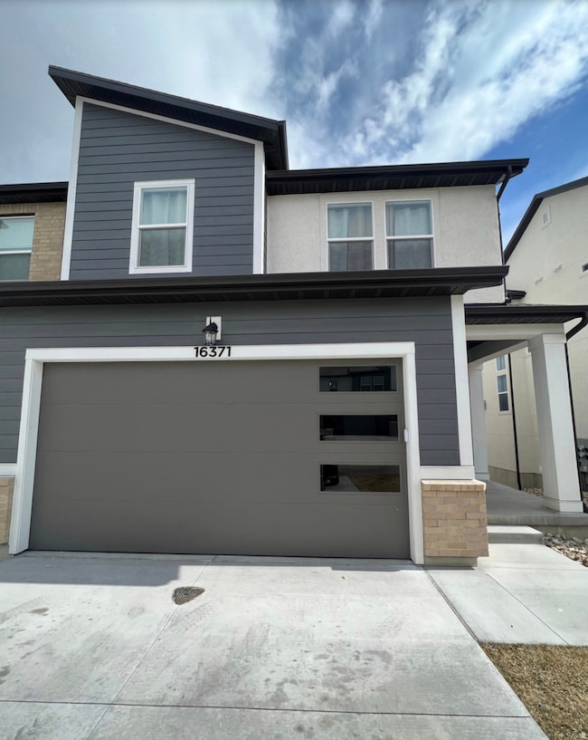 View of front of home featuring concrete driveway, a porch, and an attached garage