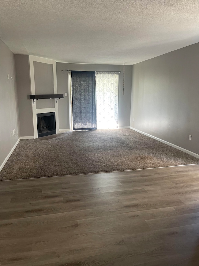 Unfurnished living room featuring baseboards, a fi