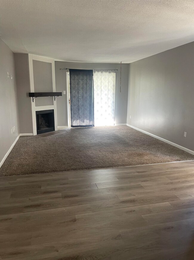 Unfurnished living room featuring baseboards, a fi