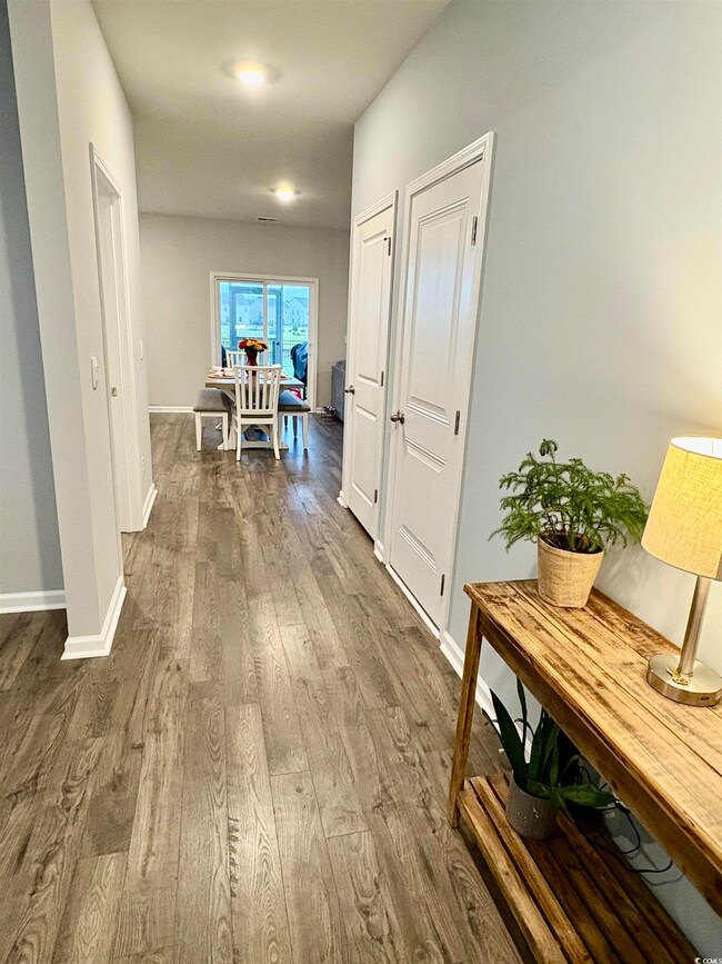 Corridor with dark wood-type flooring and baseboards