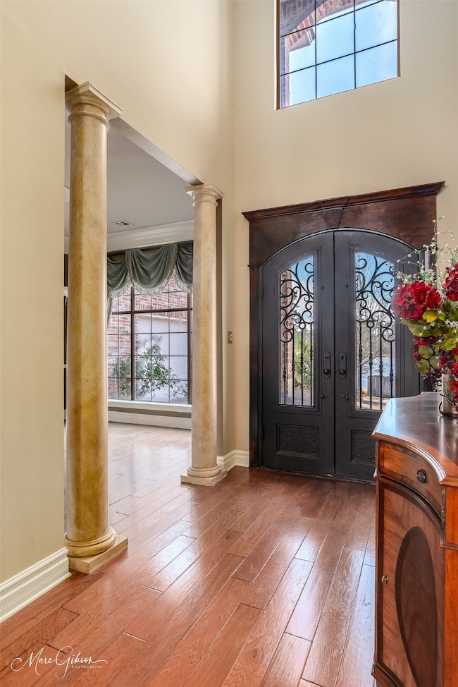 Entryway with hardwood / wood-style flooring, ornamental molding, french doors, and decorative columns