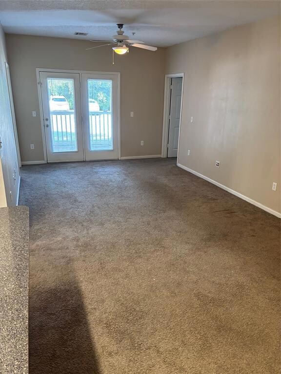 Living room featuring ceiling fan and dark carpet