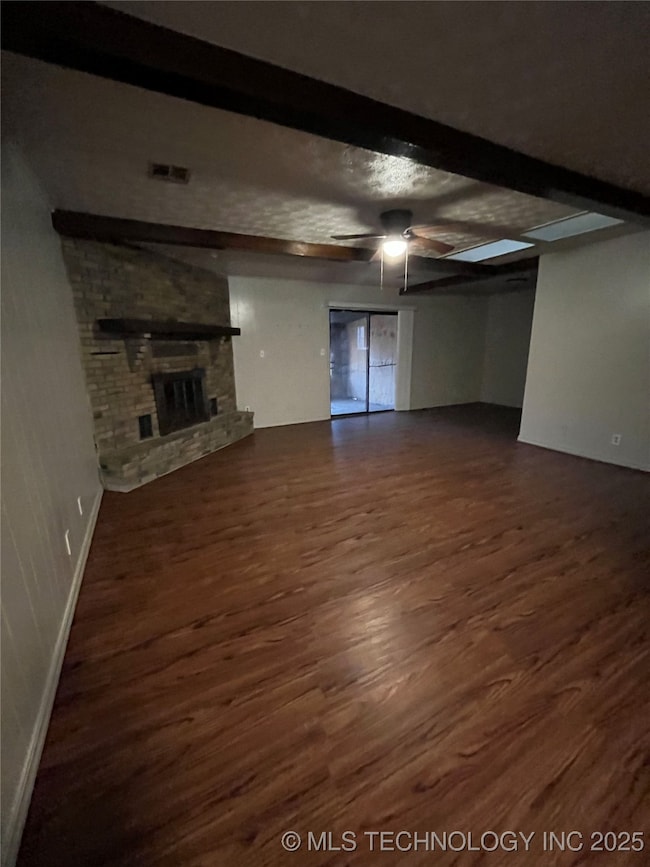 Unfurnished living room featuring beam ceiling, da