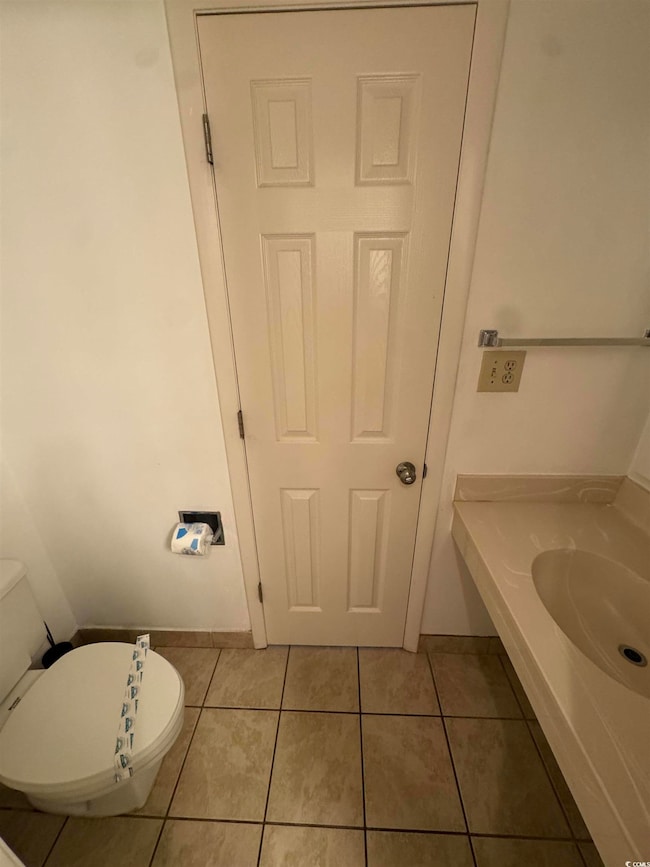 Half bathroom with tile patterned flooring, toilet
