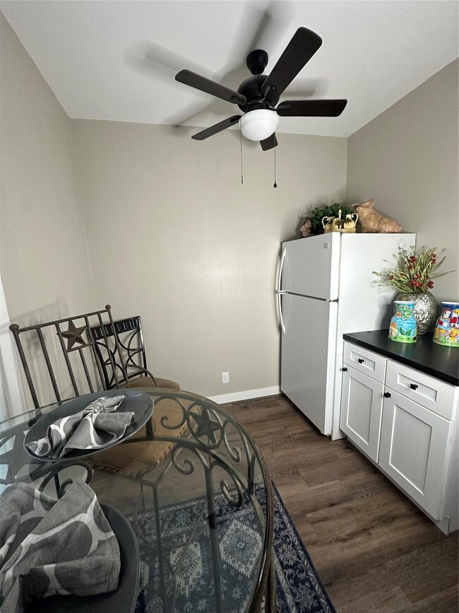 Bedroom with dark wood-type flooring, ceiling fan, and refrigerator