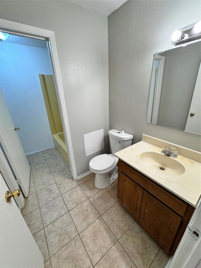 Bathroom featuring tile flooring, vanity, and toil